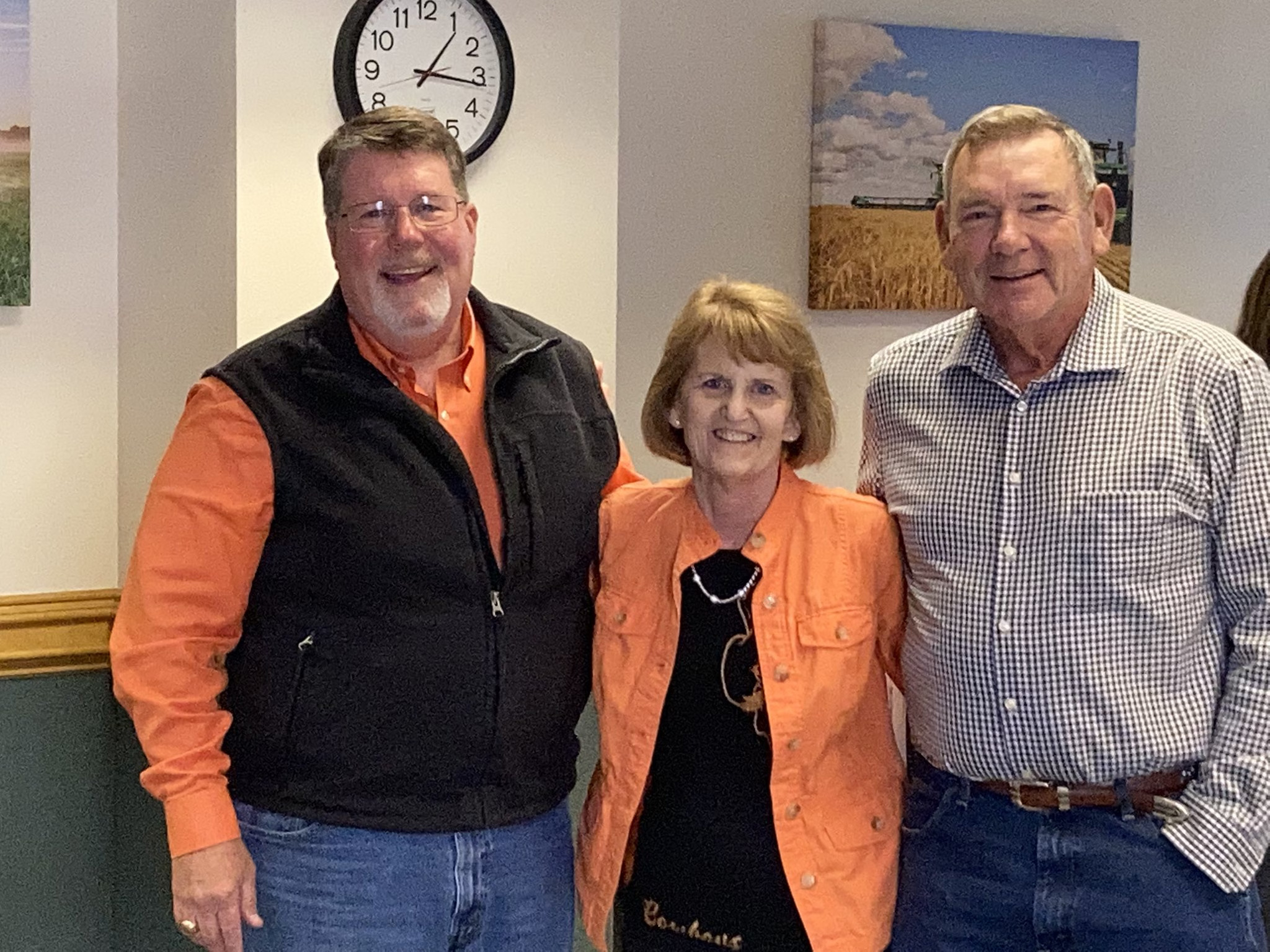 Three people standing with their arms around each other.