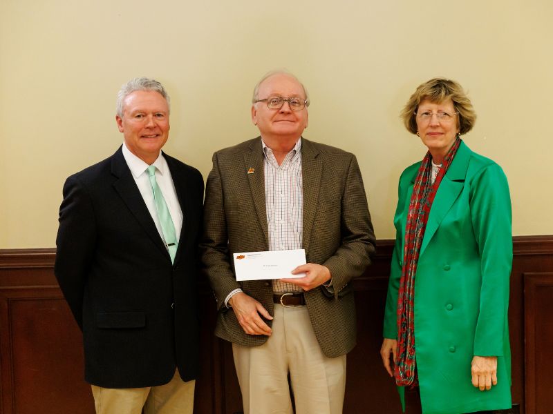 Dr. Edwards receiving his award standing in the middle of two other OSU Agriculture employees. All three dressed in nice business clothes, Edwards holding an envelope.