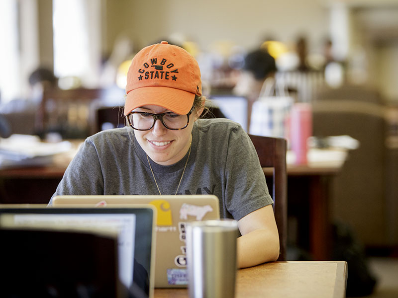 A girl with an orange cap sitting with her laptop.