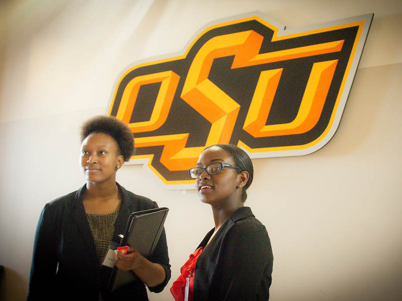 Two women standing in front of the OSU logo. 