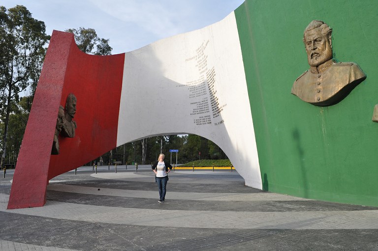Student standing under an art sculpture of Mexico's flag in Mexico.