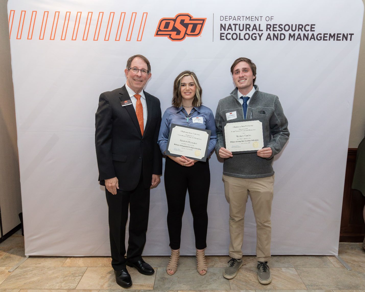Jim Ansley next to Elizabeth and Matthew accepting their Graduate Student Scholarship award.
