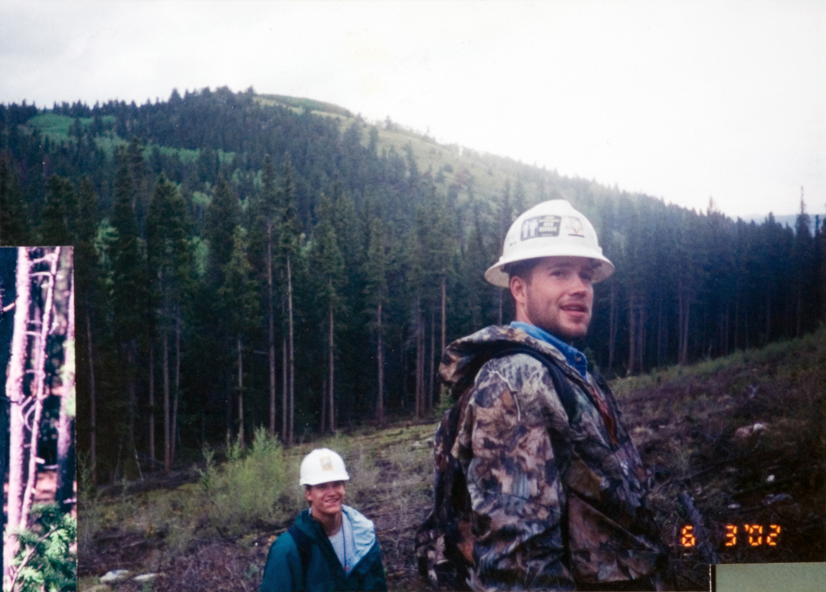 Two students in white hardhats posing for a picture as they work on a forestry job site.