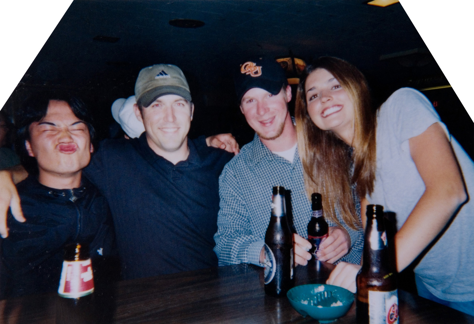 Four individuals that are smiling for a photo at a local bar.