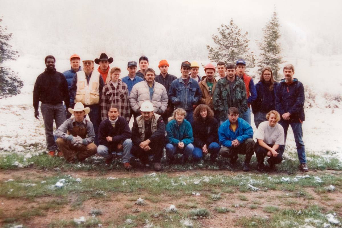 A large group of students gather for a group photo in a snowy valley. 