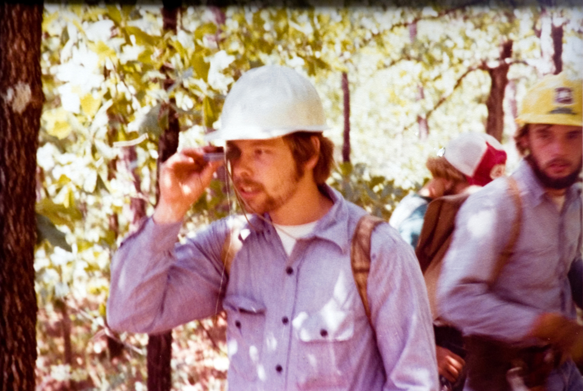 Students outside in a forest wearing hardhats.