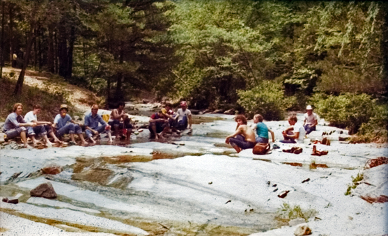 A group of students sitting near a stream.