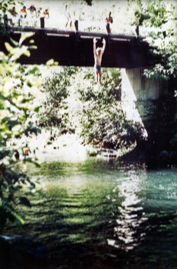 A student makes the jump off a bridge into the water.