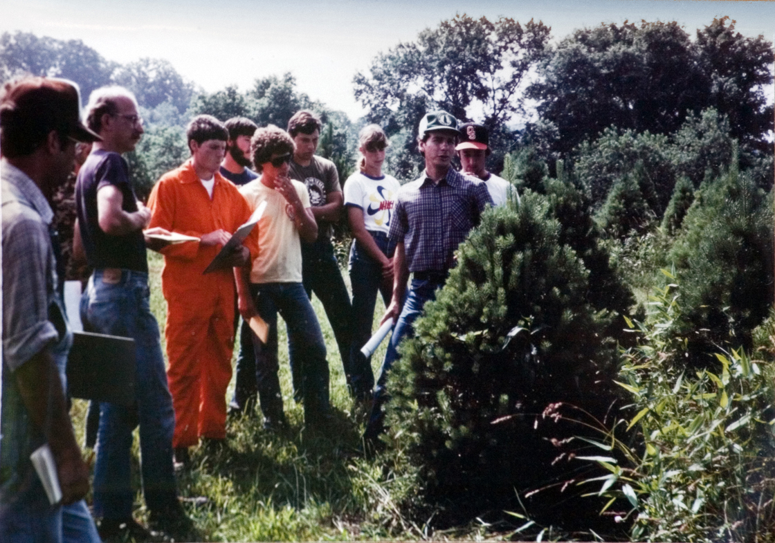Students stand together listening to instructor.