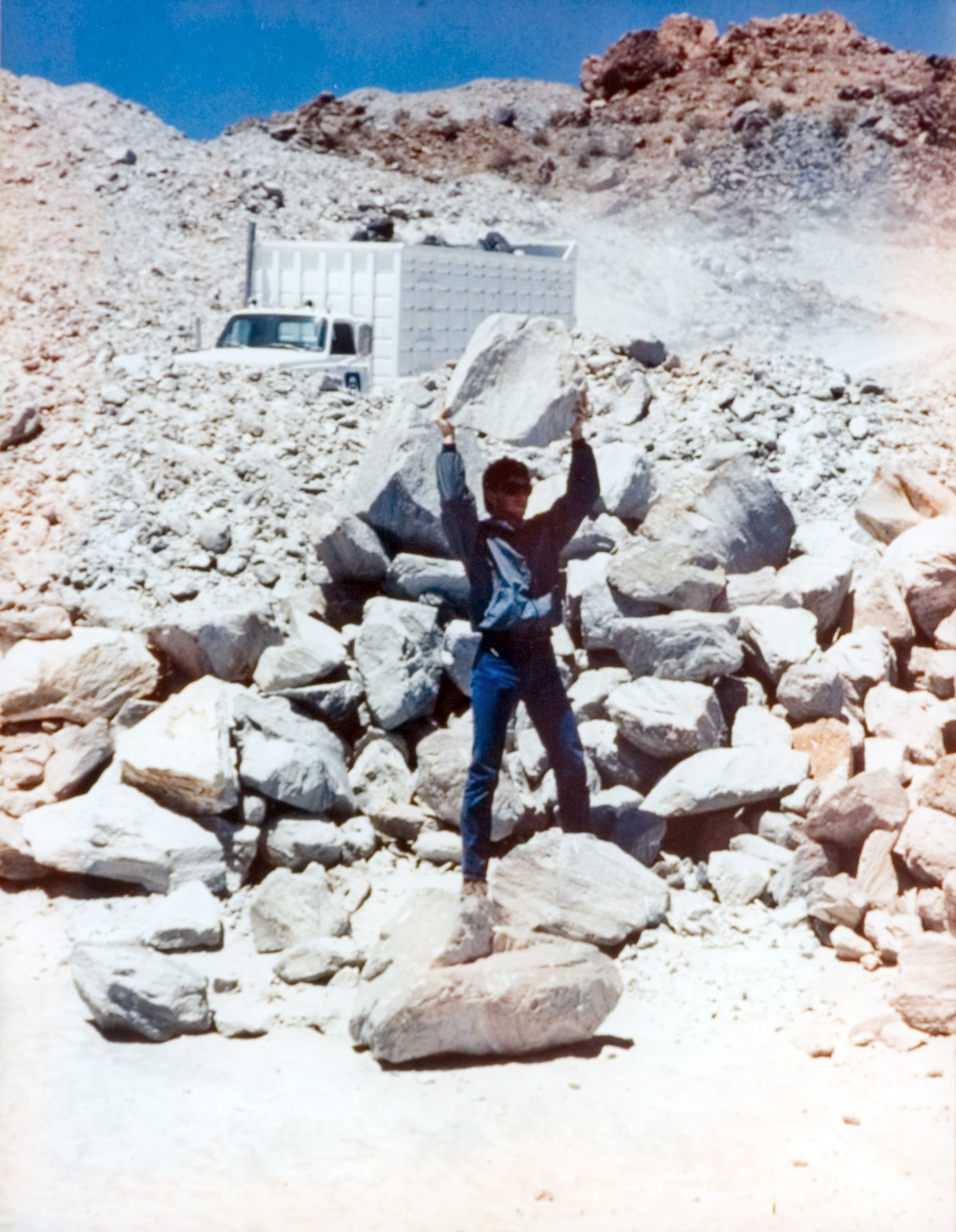 Students displays his strength as he holds up a boulder at a quarry.