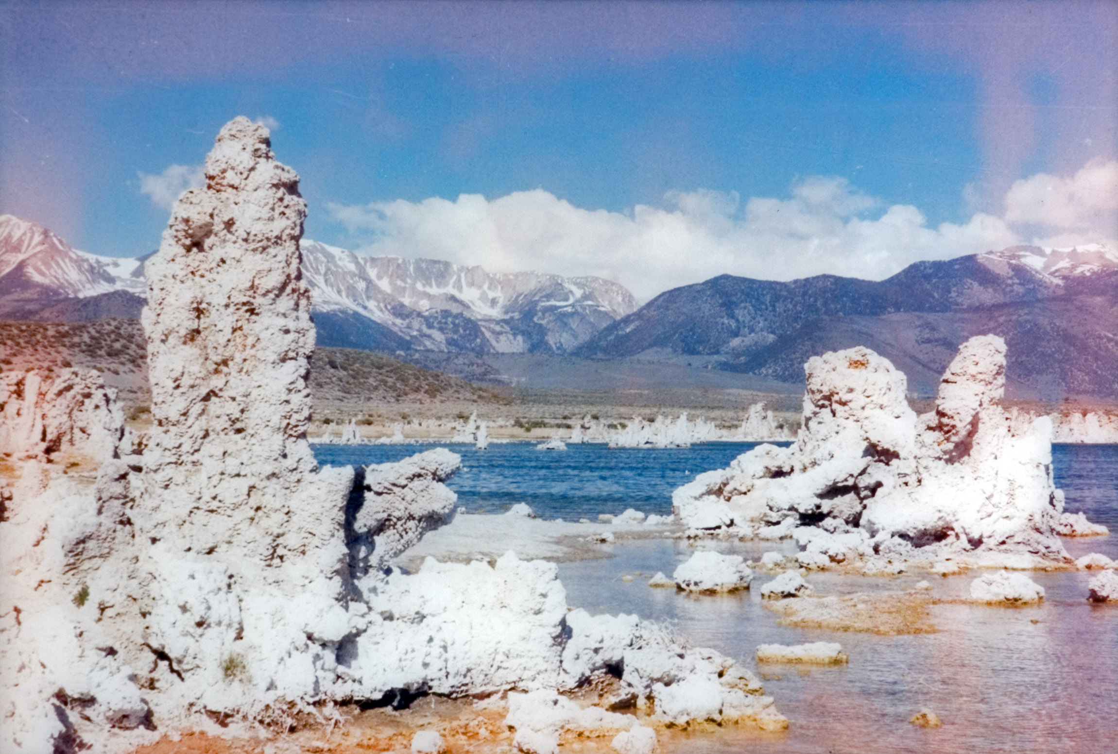 Scenic view of rock formations by the lake with mountains in the background.