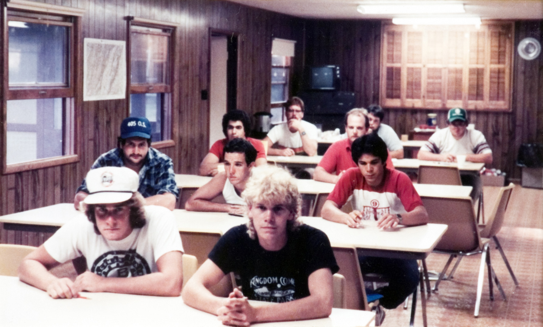 A group of students sitting at desks inside of a classroom as they await for an instructor.