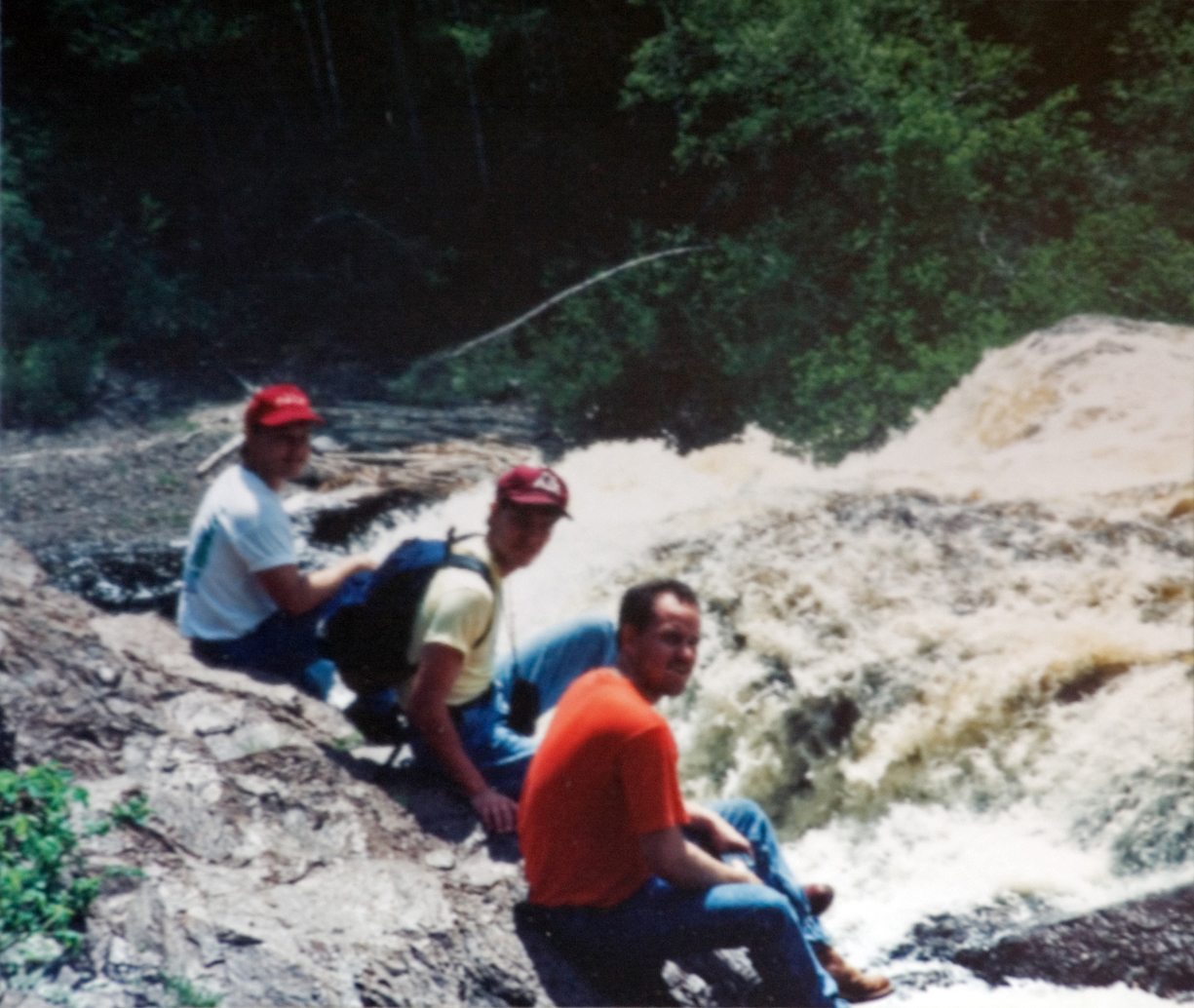 Three students sitting by the rushing water enjoying the view.