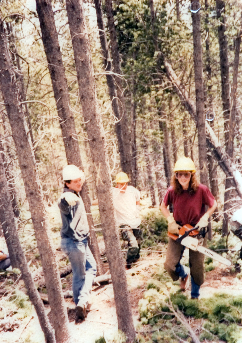 Students in hardhats out on the job in the woods. 