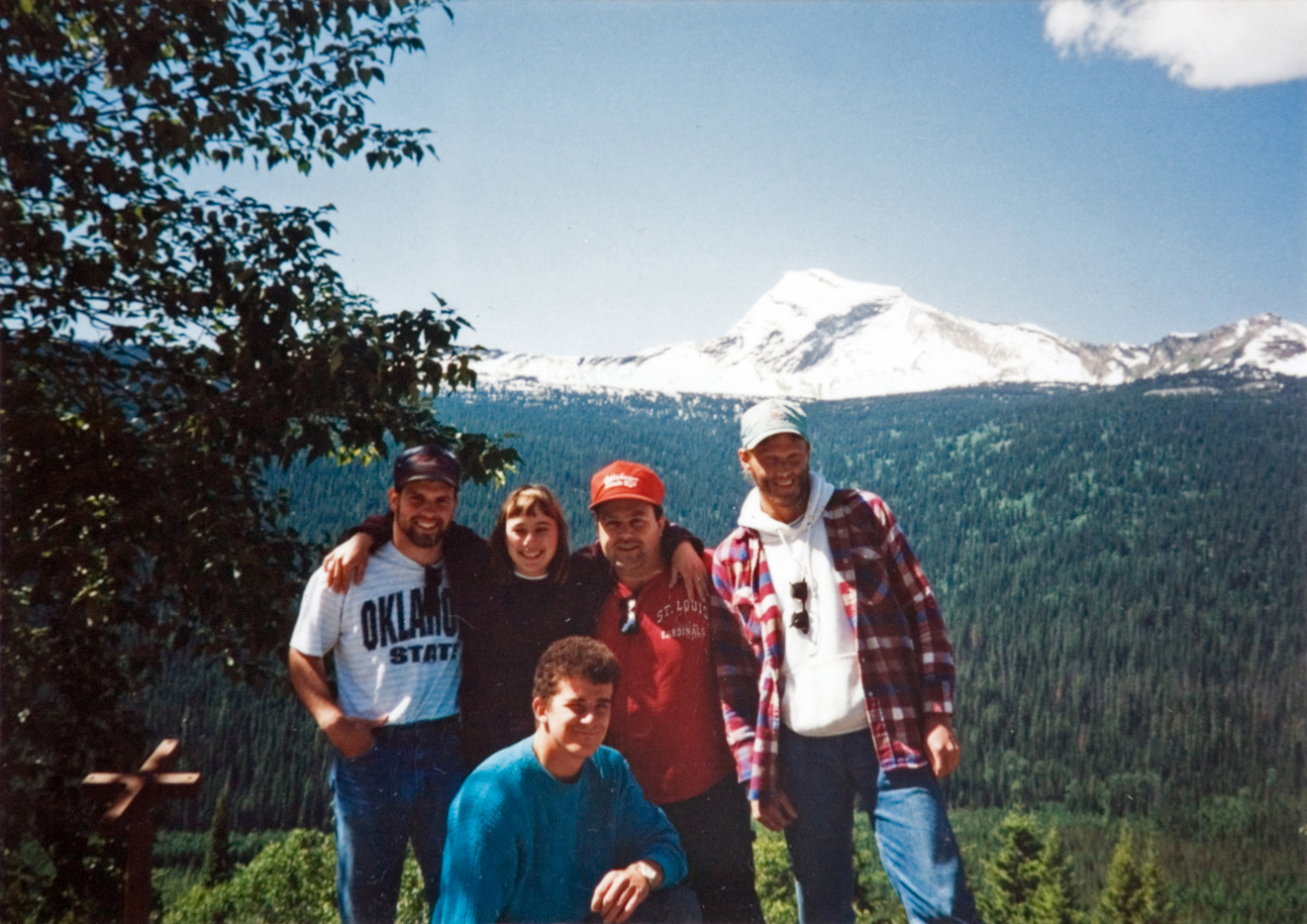 Five people standing together which a snowy mountain in the background.