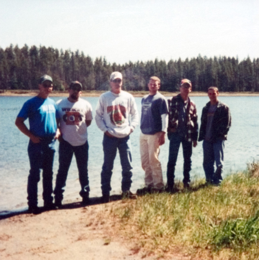 A group of six students standing in front of a lake as they pose for a photo