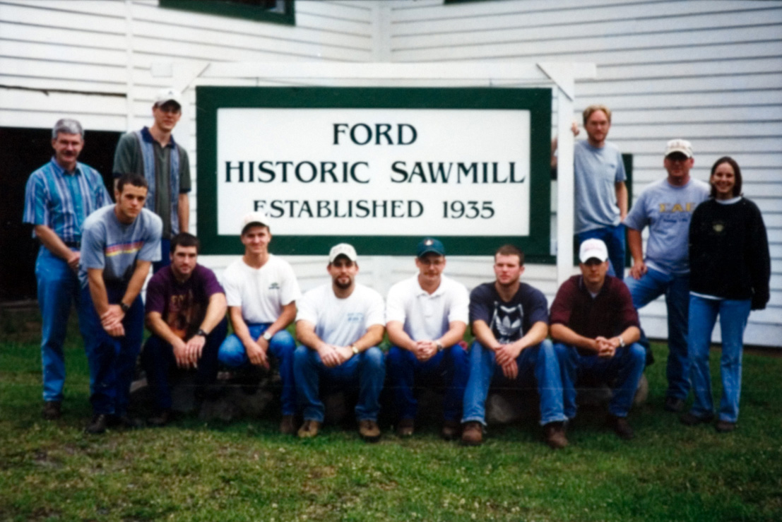 A group of students apart of the forestry camp standing in front of a sign that says 