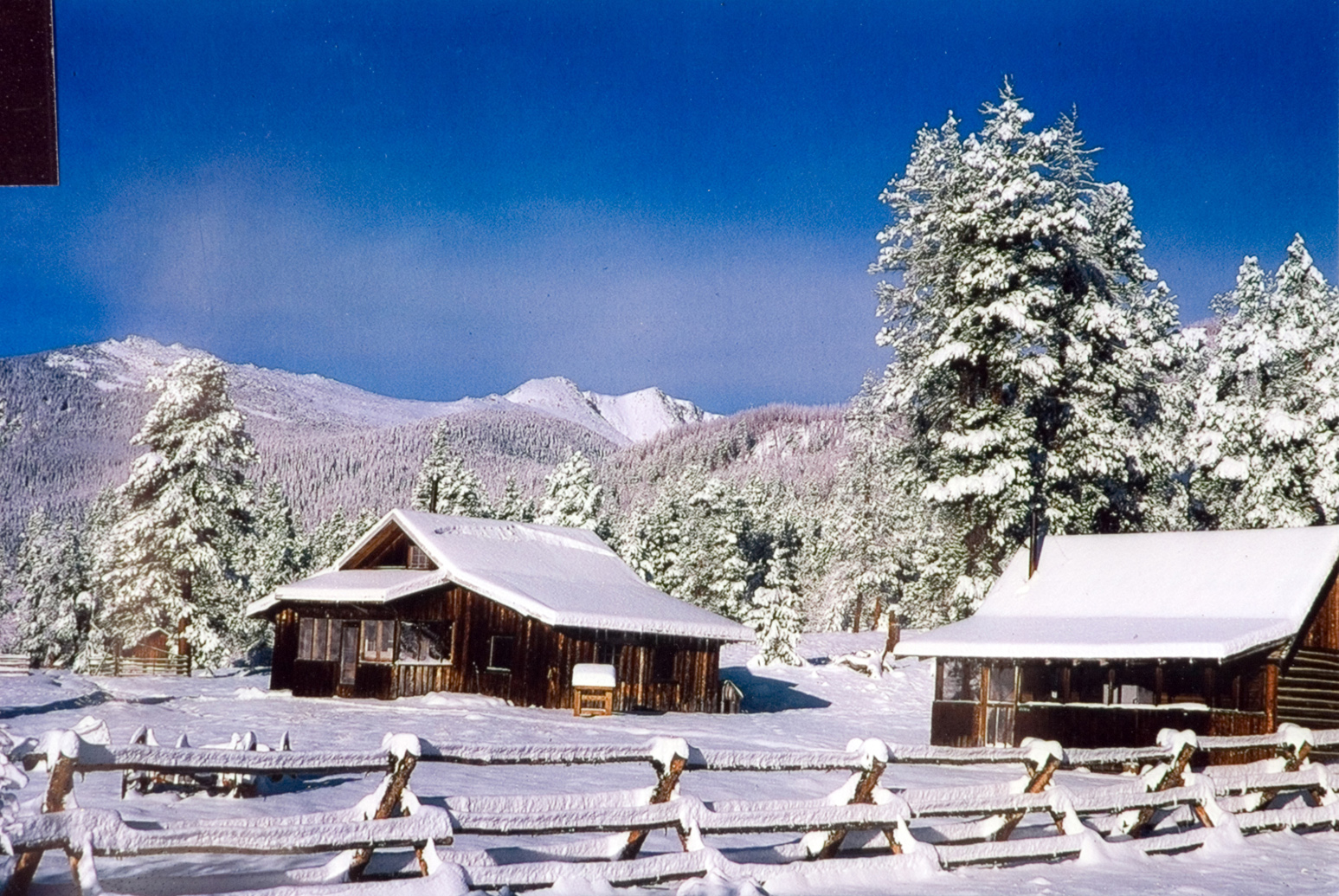A scenic view of cabins next to the snow in the mountains.