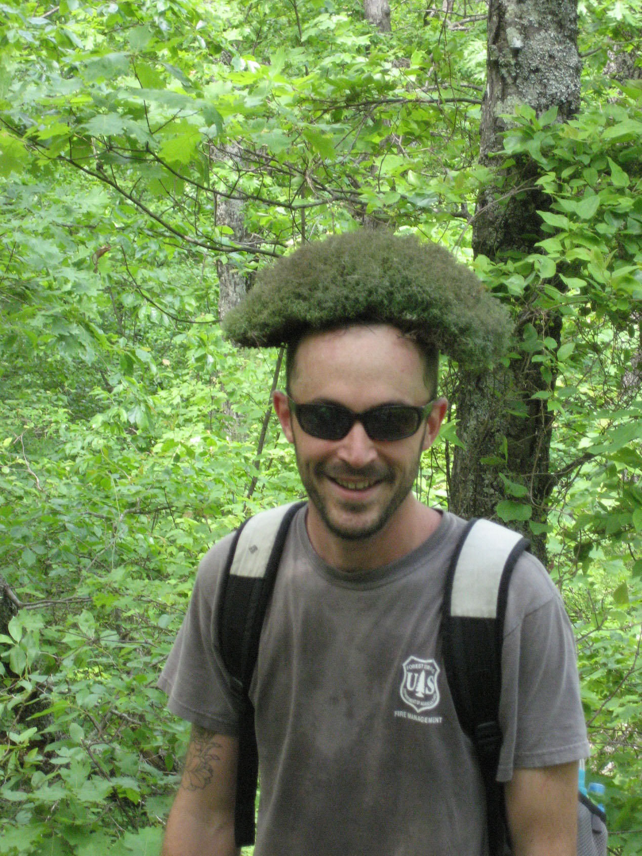 A student in the woods with a plant sitting on his head. A student in the woods with a plant sitting on his head.