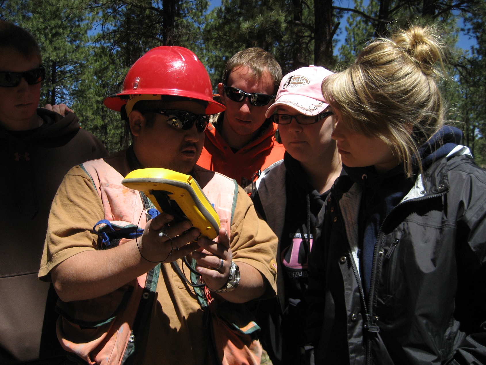 A group of participants working together to read information off a tool being used to collect data outside. A group of participants working together to read information off a tool being used to collect data outside.