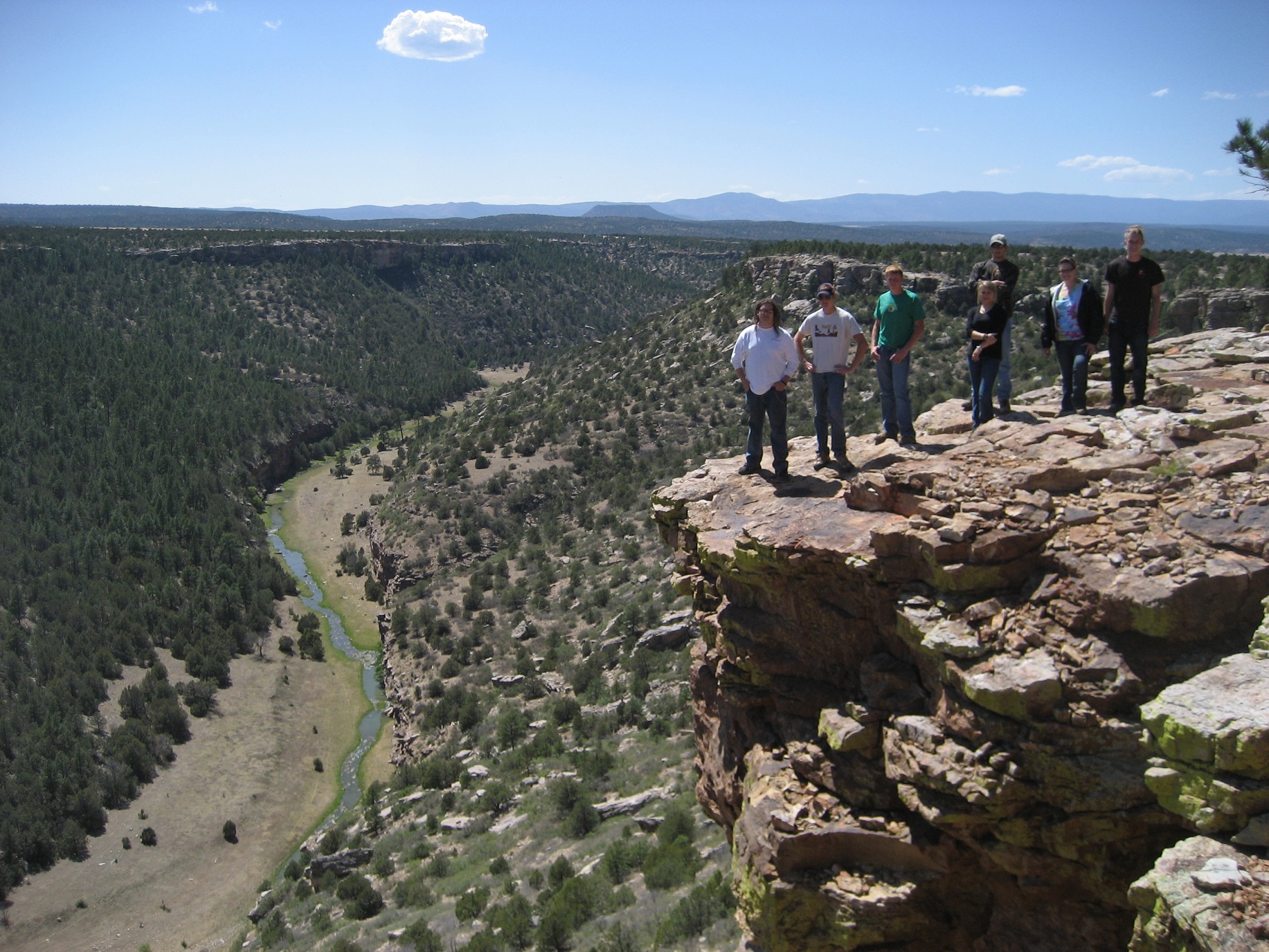 A group of students standing at the edge of a cliff overlooking a stream below. A group of students standing at the edge of a cliff overlooking a stream below.