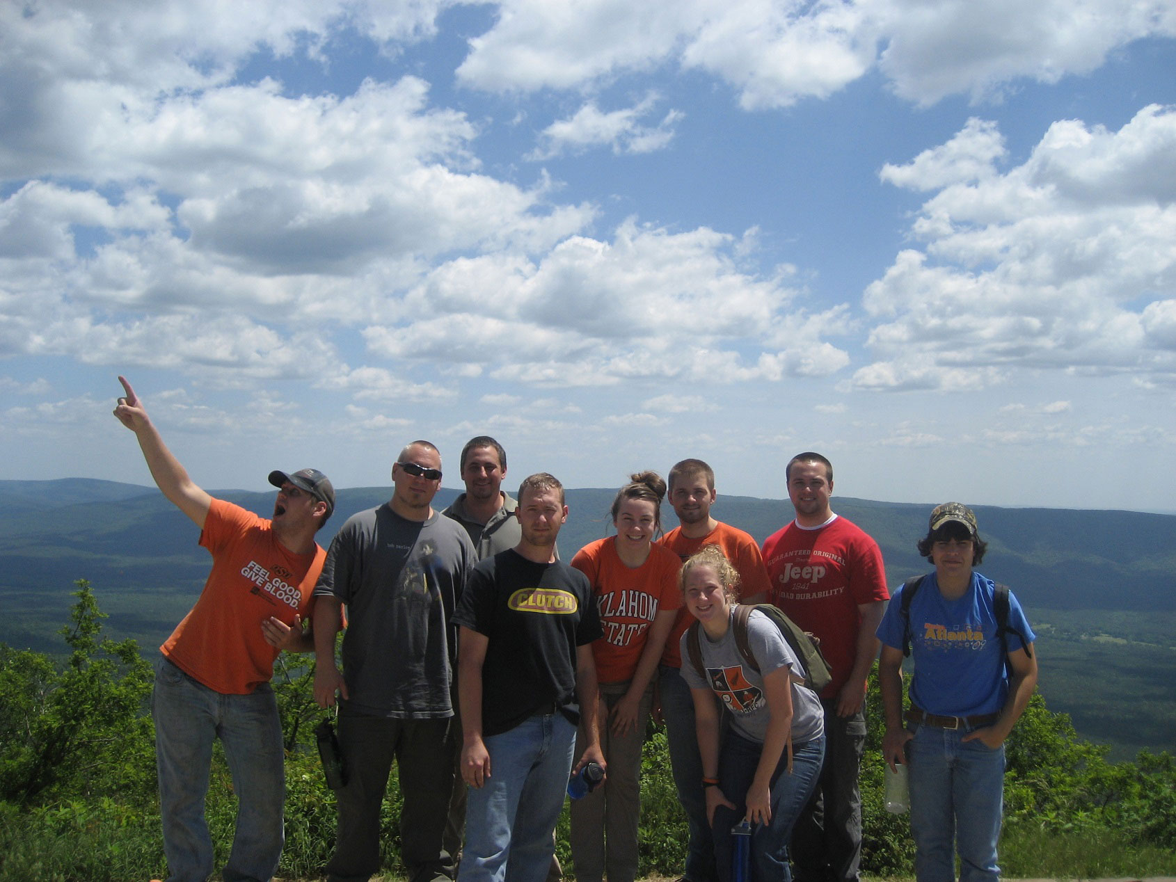 Pariticpants posing in front of an overlook of a mountain range. 