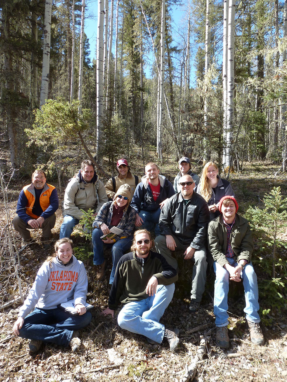 A large group photo of participants in a forest. 