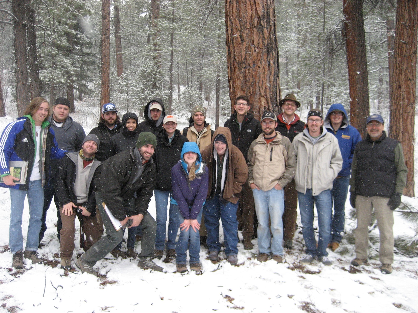 Several participants standing in a forest in the snow. 