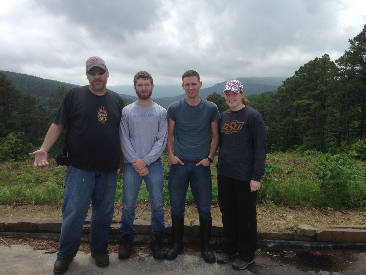 Four people standing at an overlook of a mountain range. 