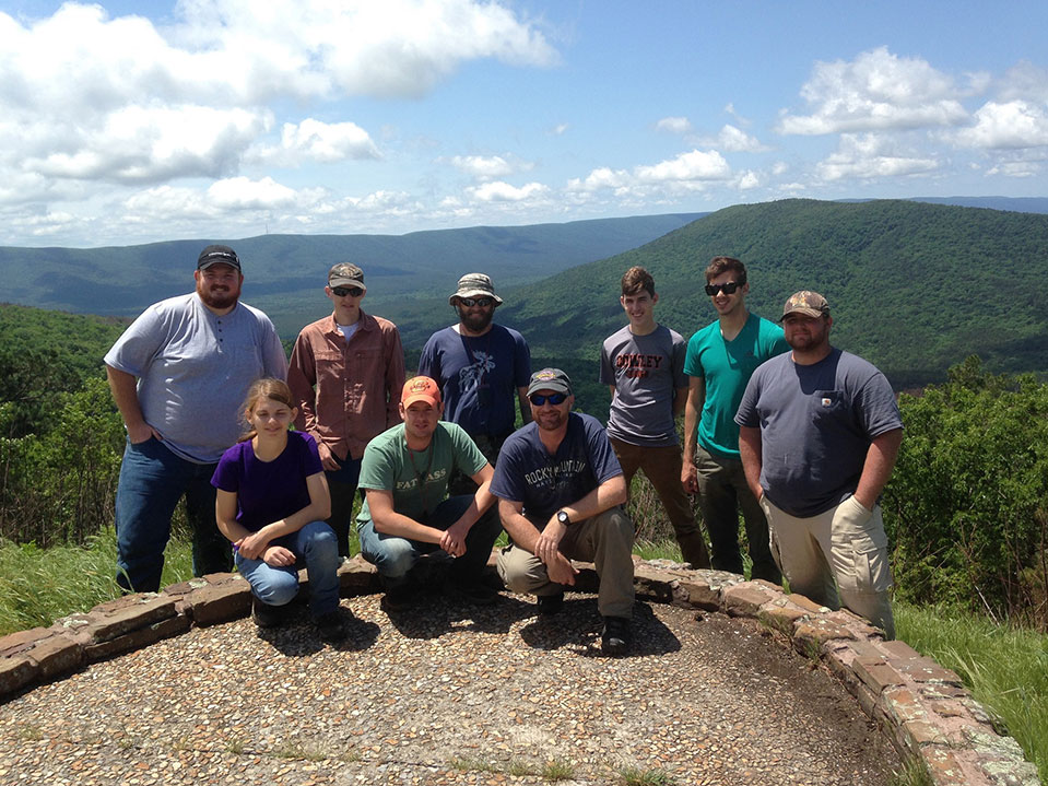 A group photo of nine people overlooking a mountain range. A group photo of nine people overlooking a mountain range.