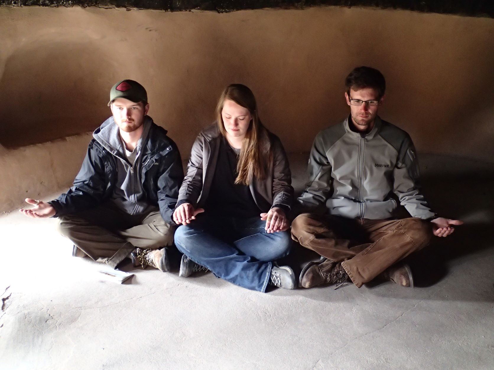 Three people sitting with their legs crossed in a cave. Three people sitting with their legs crossed in a cave.