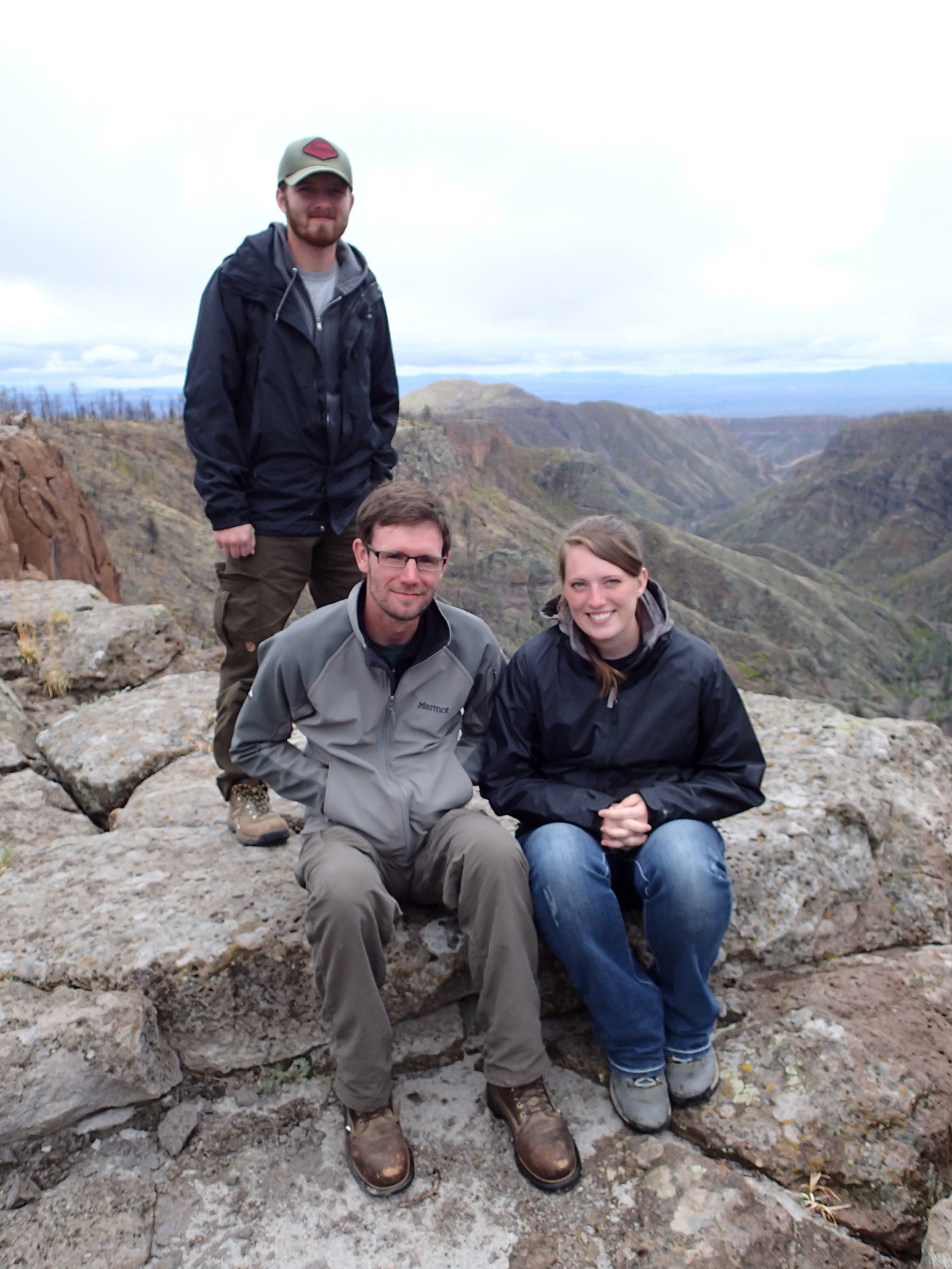 Three people at the top of a mountain overlooking the rest of the mountain range. Three people at the top of a mountain overlooking the rest of the mountain range.
