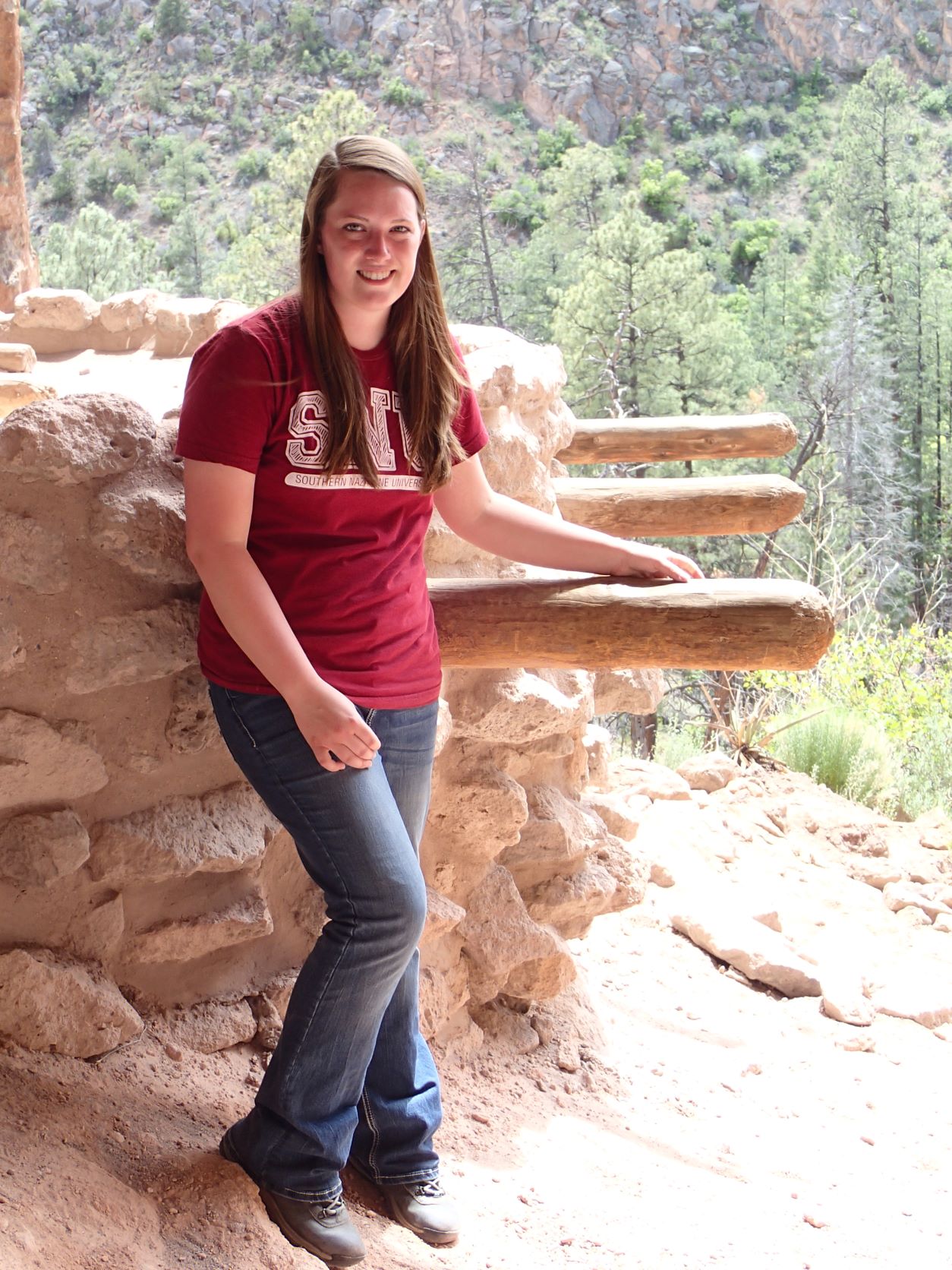 A girl standing by a rock formation with wooden posts sticking out from it. A girl standing by a rock formation with wooden posts sticking out from it.