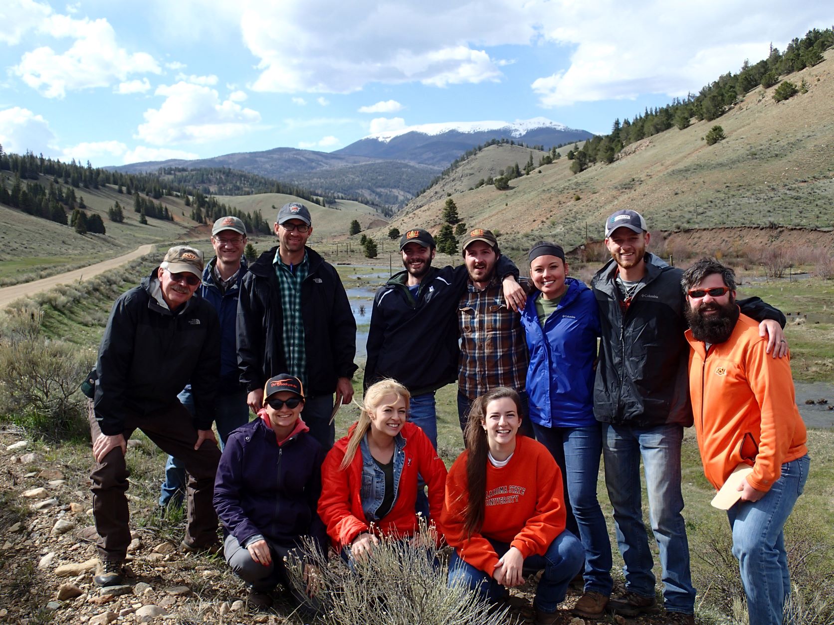 A group of 11 people standing in a valley between mountains. 