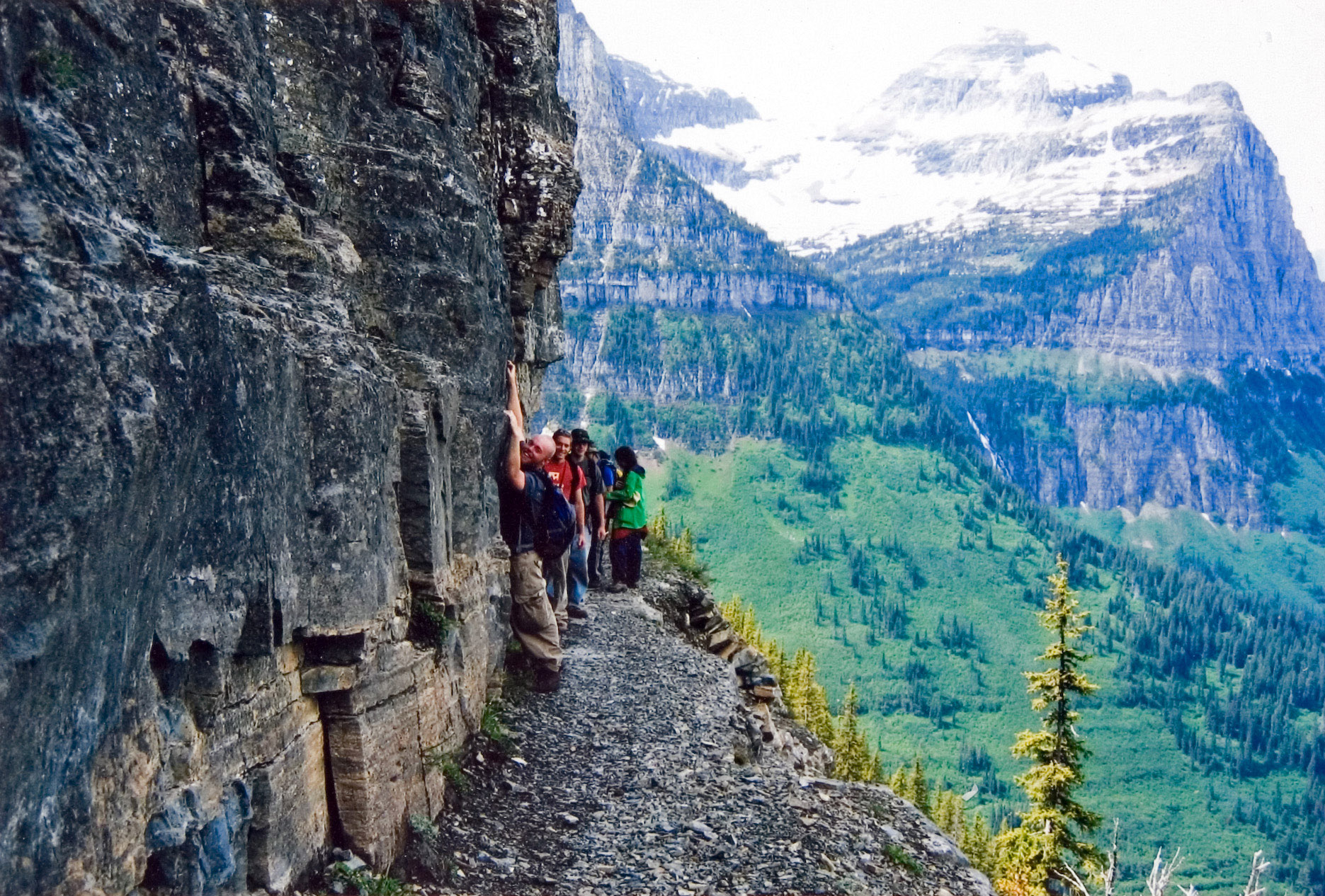 Students hugging a mountain wall while making their way through a hiking trail.