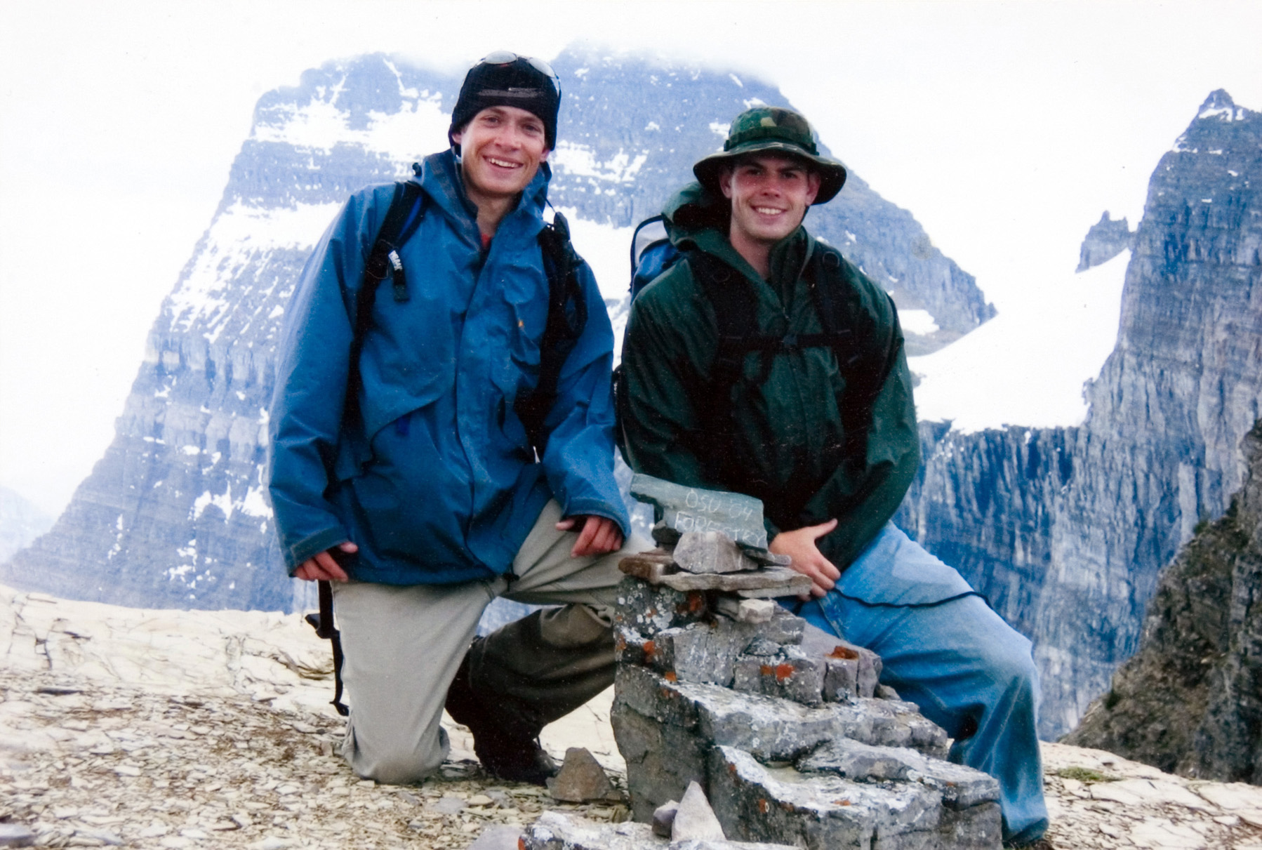 Two student kneeling and posing by a trail marker.