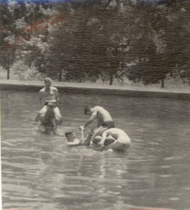 People are in the water with one person on another's shoulders while others swim around them.