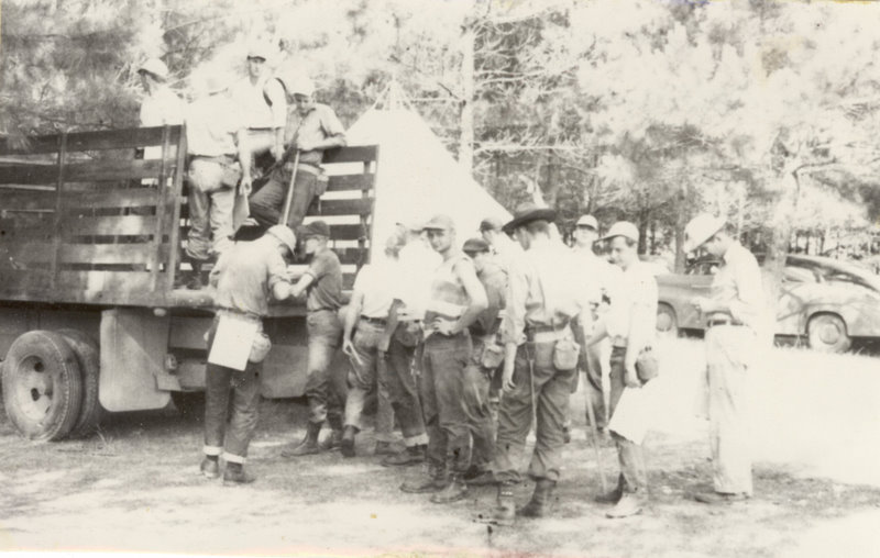 Students in the back of a truck and standing around the truck.