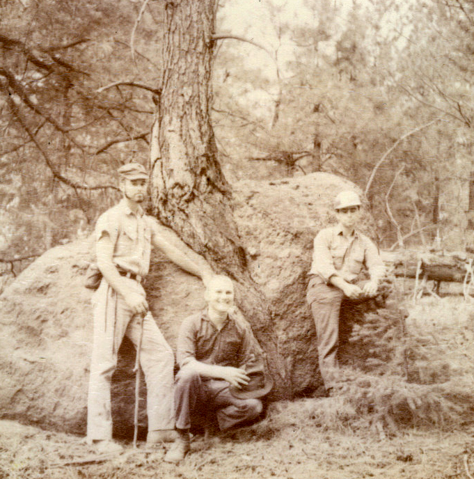 Three students posting near a rock outside. Three students posting near a rock outside.