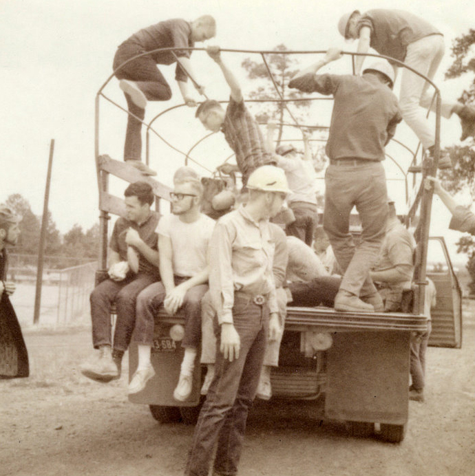 A group of people sitting on the back of a truck. A group of people sitting on the back of a truck.
