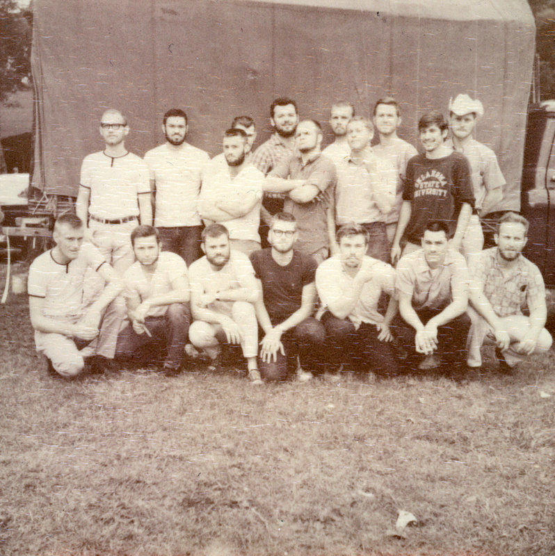 A group of students sitting outside in front of a building. A group of students sitting outside in front of a building.