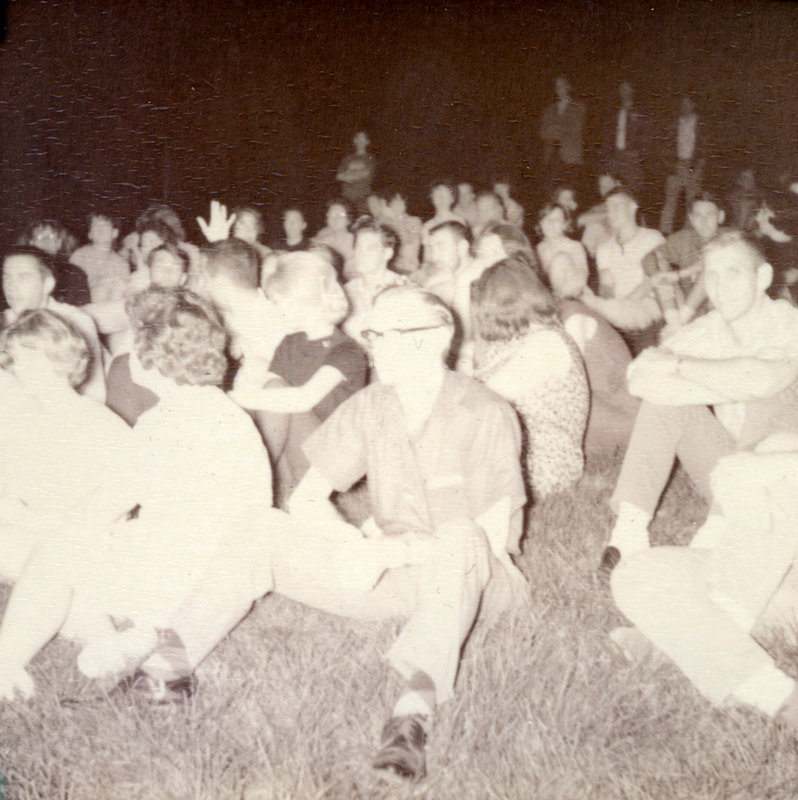 A group of people sitting in grass. A group of people sitting in grass.