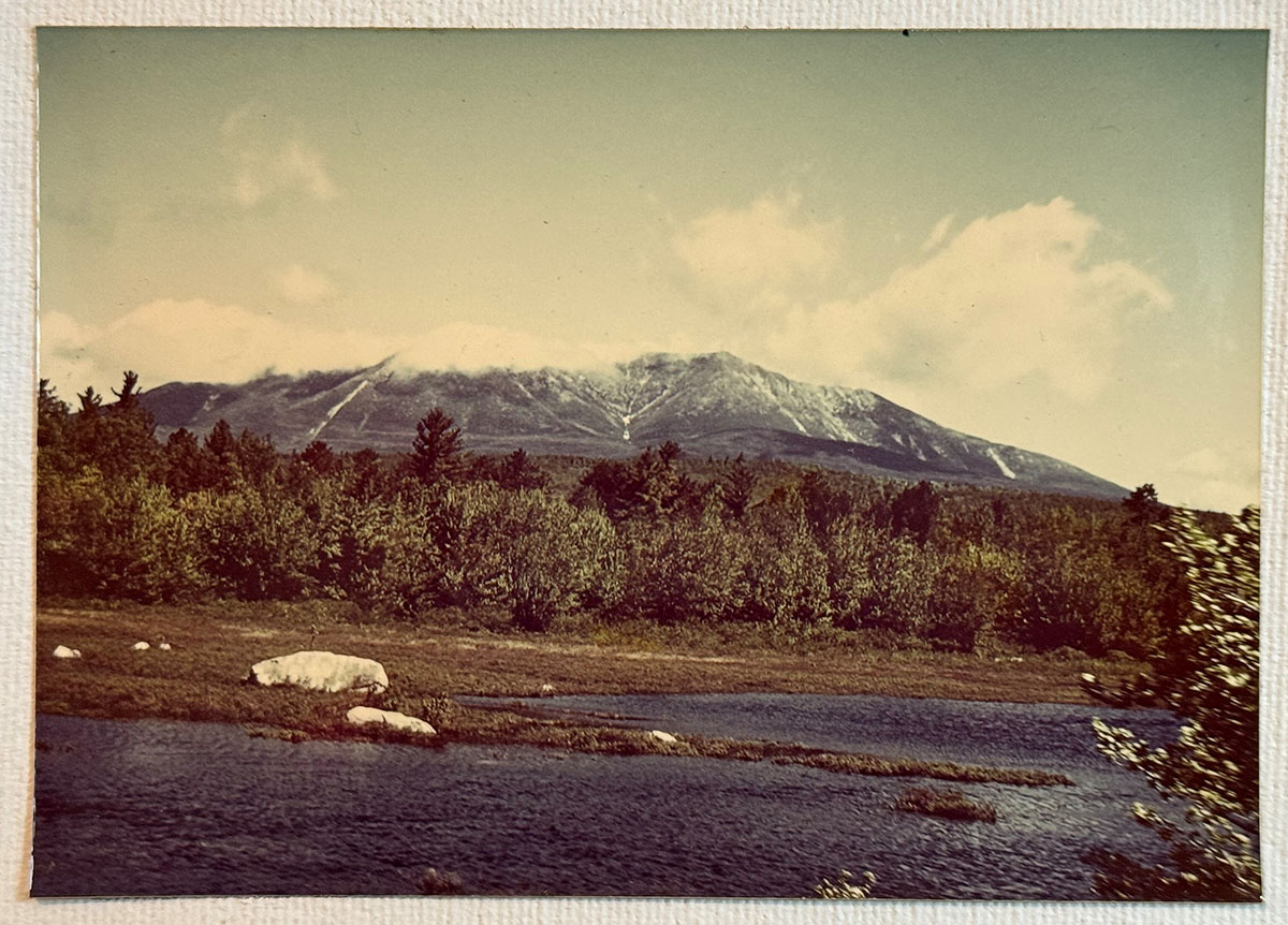 A blue river in the front, dark green trees in the middle and a mountain in the background. A blue river in the front, dark green trees in the middle and a mountain in the background.