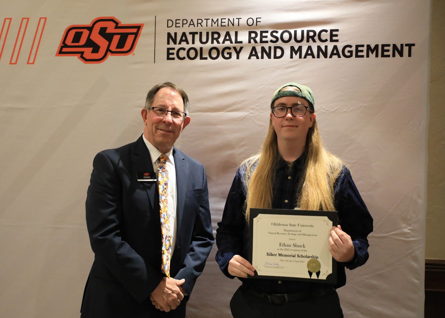 Ethan Shuck showing off his scholarship plaque next to Dr. Jim Ansley.