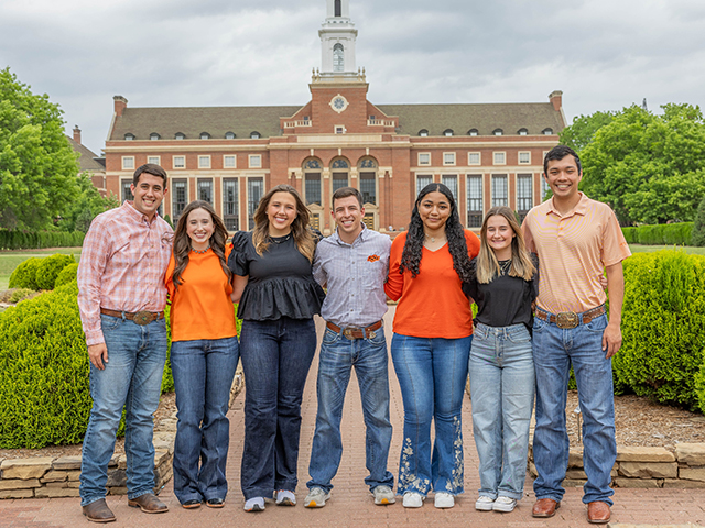 A group of Ferguson College students stand in front of Edmon Low Library. 